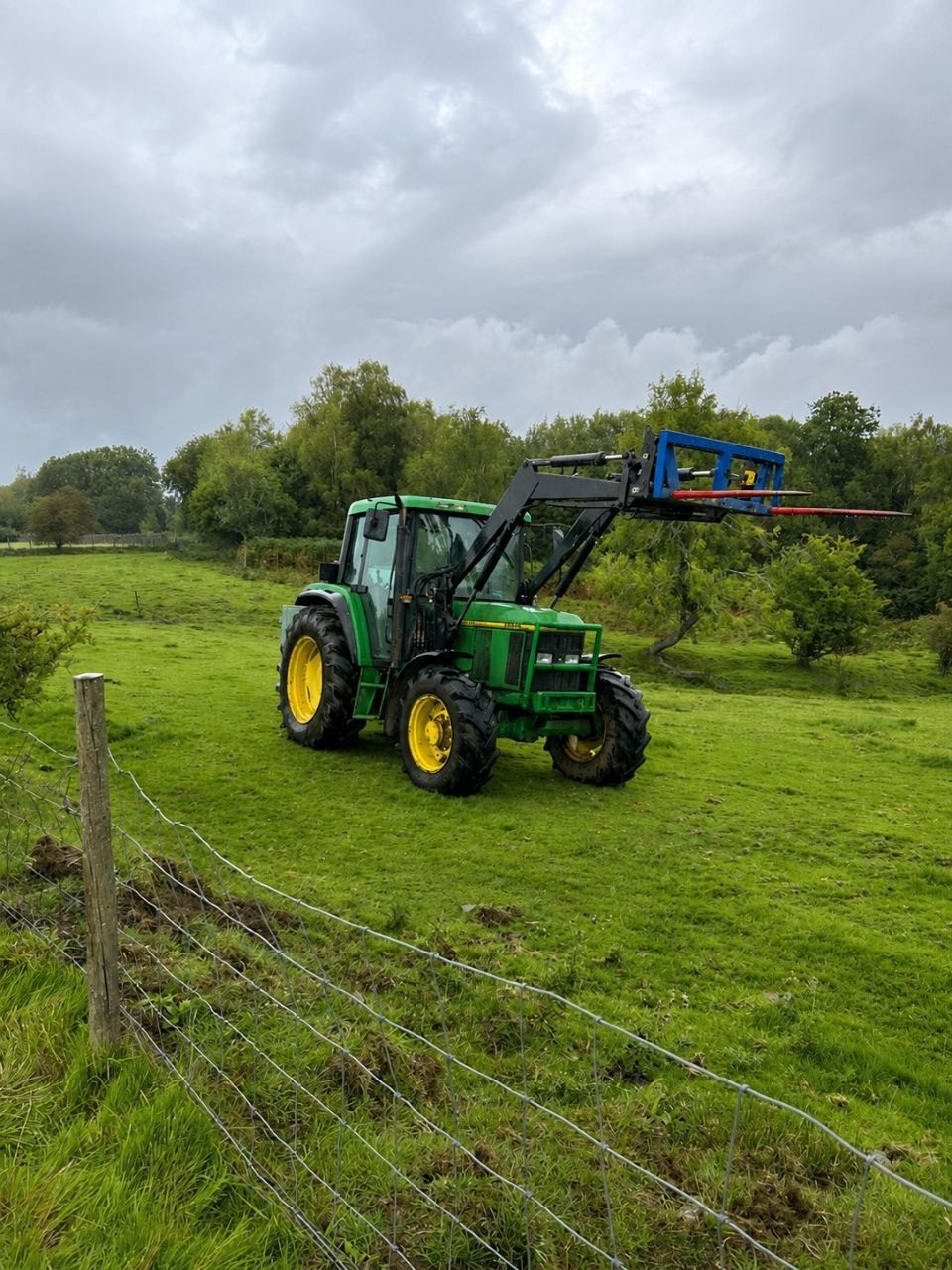 John Deere tractor with spreader at sunset