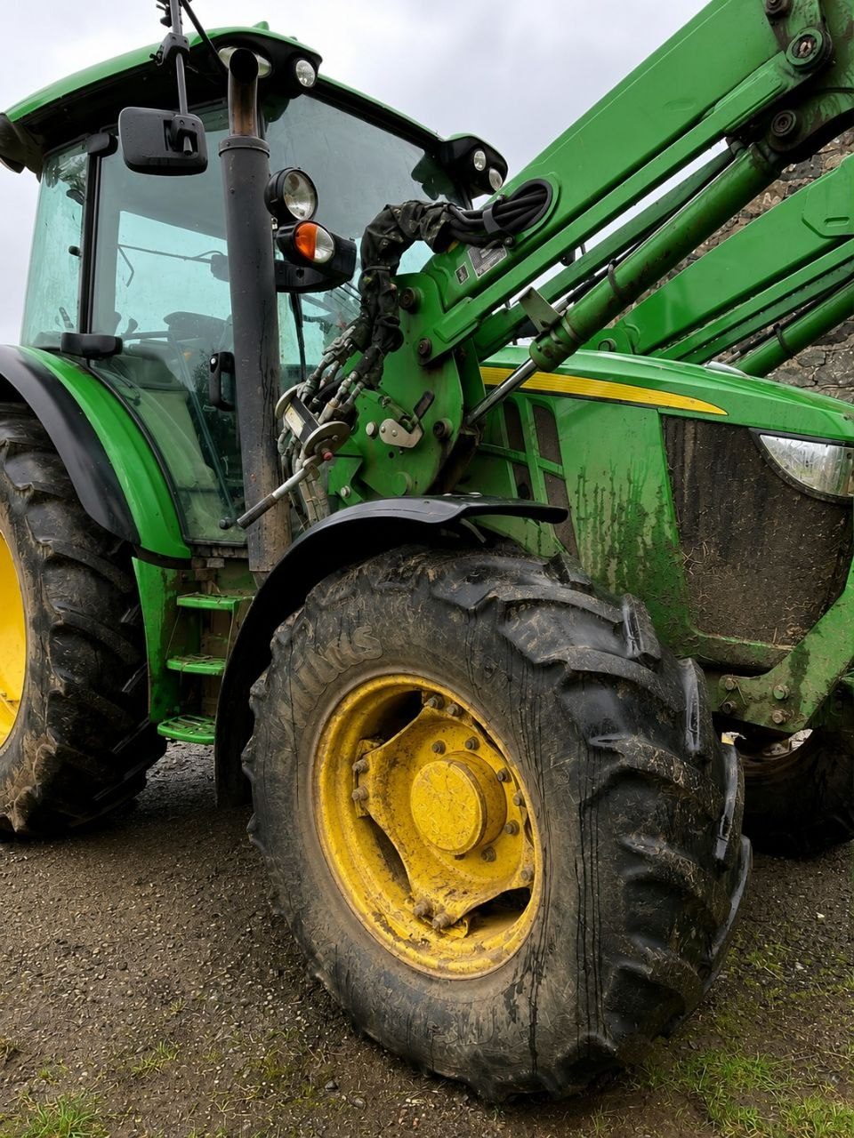 John Deere loader tractor by a stone wall