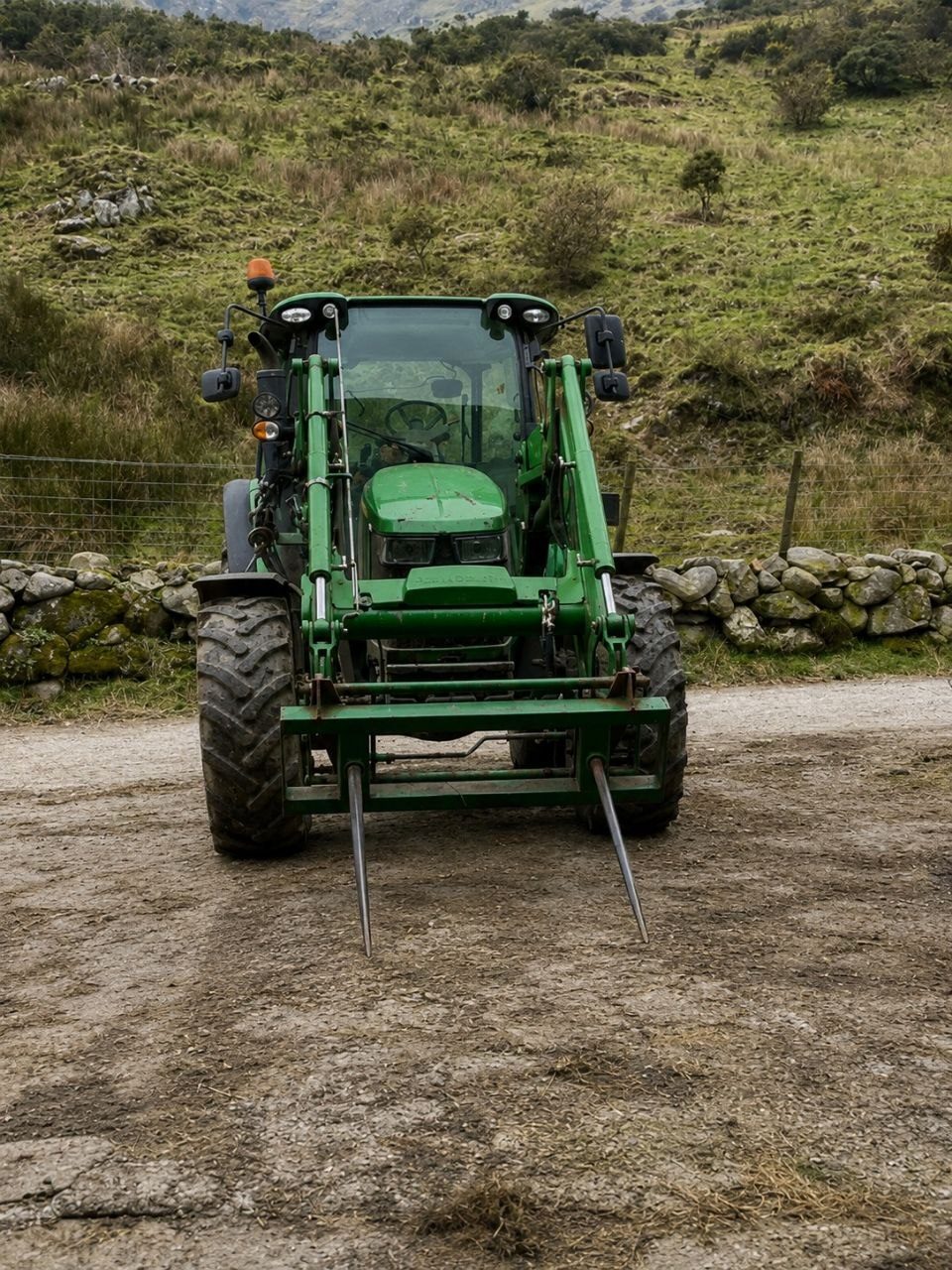 John Deere tractor with bale spike in the mountains