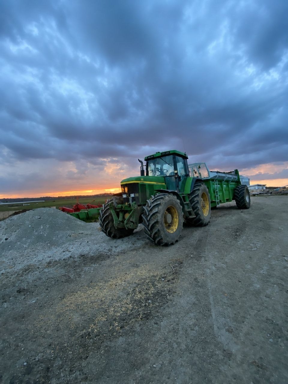 John Deere tractor moving a wrapped bale in a barn